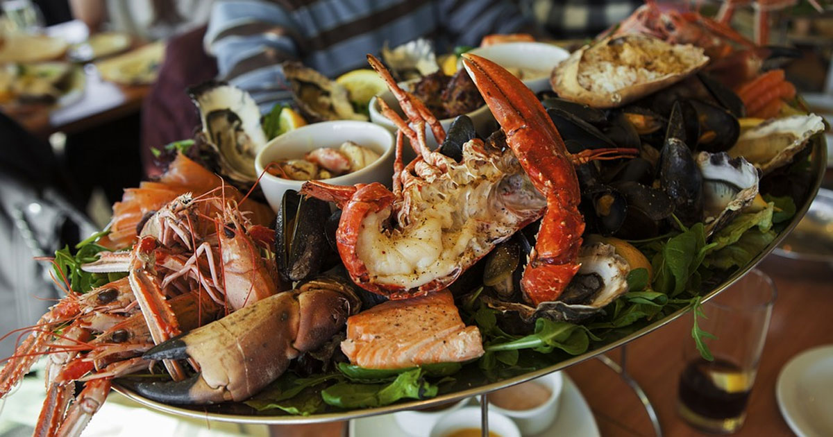 a plate of various seafood being presented by a server