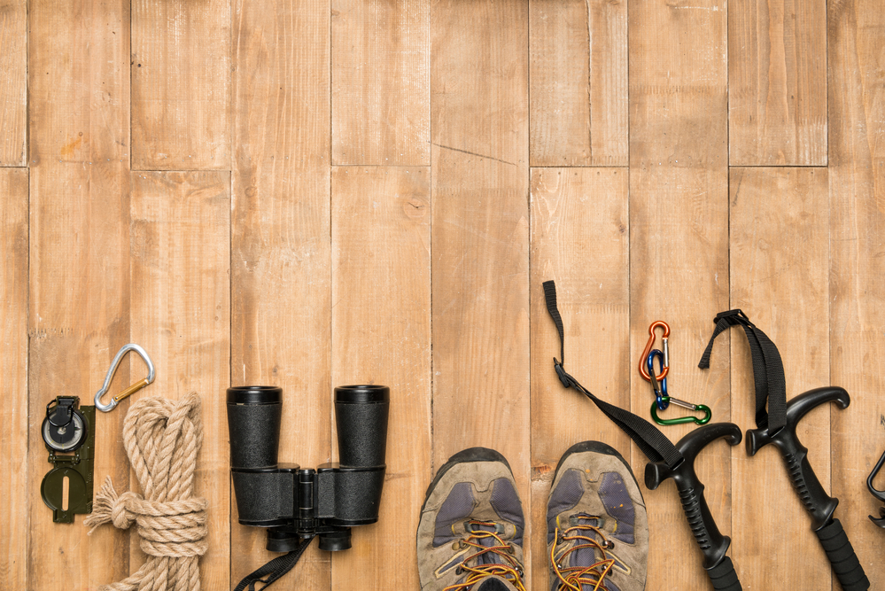 hiking boots and hiking equipment lined up on a wooden floor