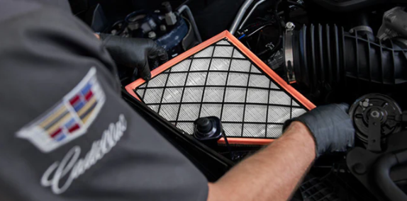 a certified Cadillac technician replacing the engine air filter in a Cadillac vehicle. 
